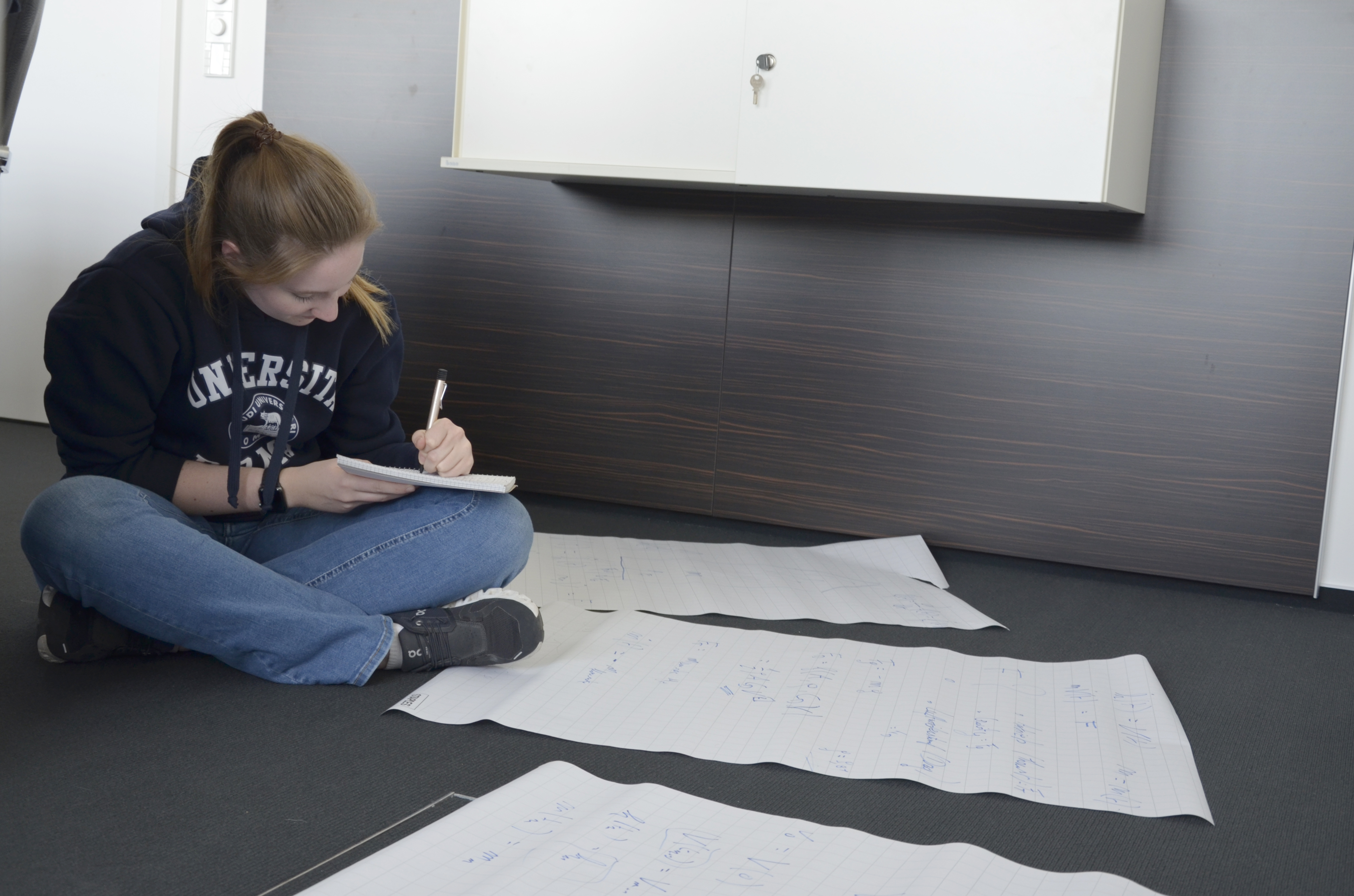 Raketengruppe: Schülerin arbeitet im Schneidersitz an Formeln