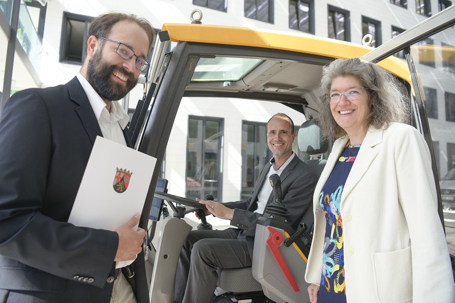 Wissenschaftsminister Clemens Hoch testet die Baggerkabine des Fahrsimulators; links Dr. Michael Burger, Koordinator des geförderten Projektes, und rechts die Leiterin des Fraunhofer ITWM, Prof. Dr. Anita Schöbel. 
