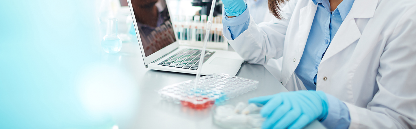 Junge Frau im weißen Kittel untersucht neue chemische Substanzen im Labor